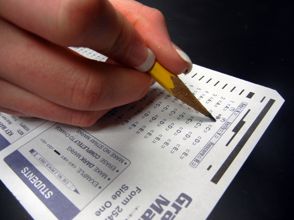 A close up of a student's hand marking a standardized test with a pencil